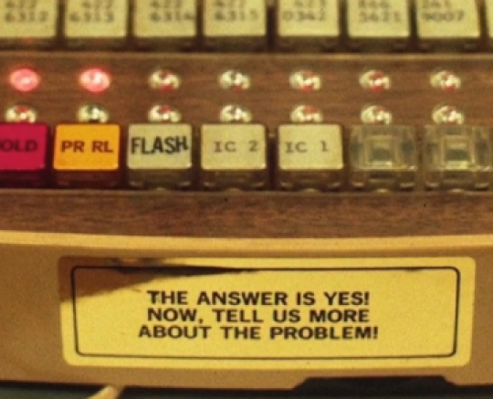 Sticker on Akers phone reminding customer service the answer is always Yes and tell us more. 